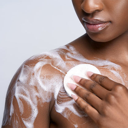 Person applying Makari Brightening Exfoliating Antiseptic Soap to their shoulder with a white background