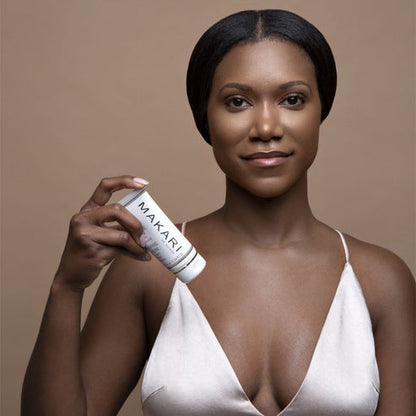 Woman holding a Makari De Suisse Clarifying Cream against a brown background
