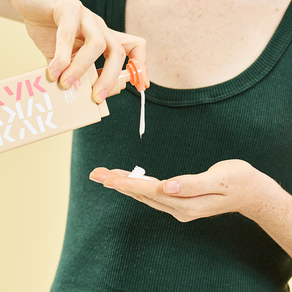 Person applying Makari IYKYK Vitamin C + Turmeric Body Toning Cream onto their palm against a neutral background